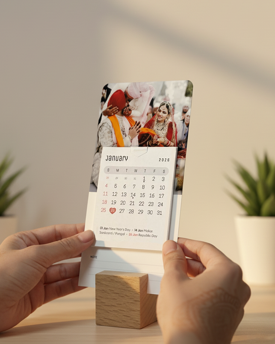 Person holding a calendar with a wooden stand on a light surface.