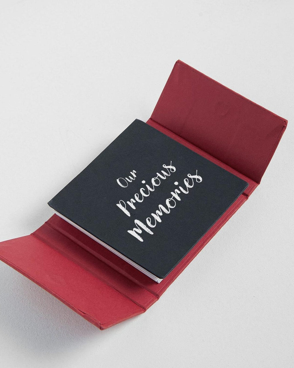 Red notebook cover with a black inner page displaying 'Our Precious Memories' on a white background