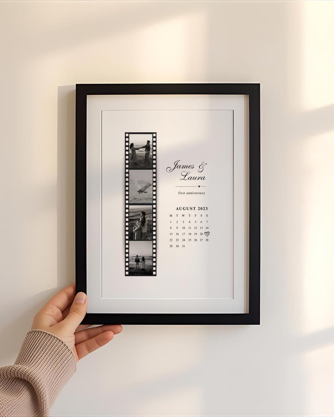 Framed photo album with film strip design held against a light wall.