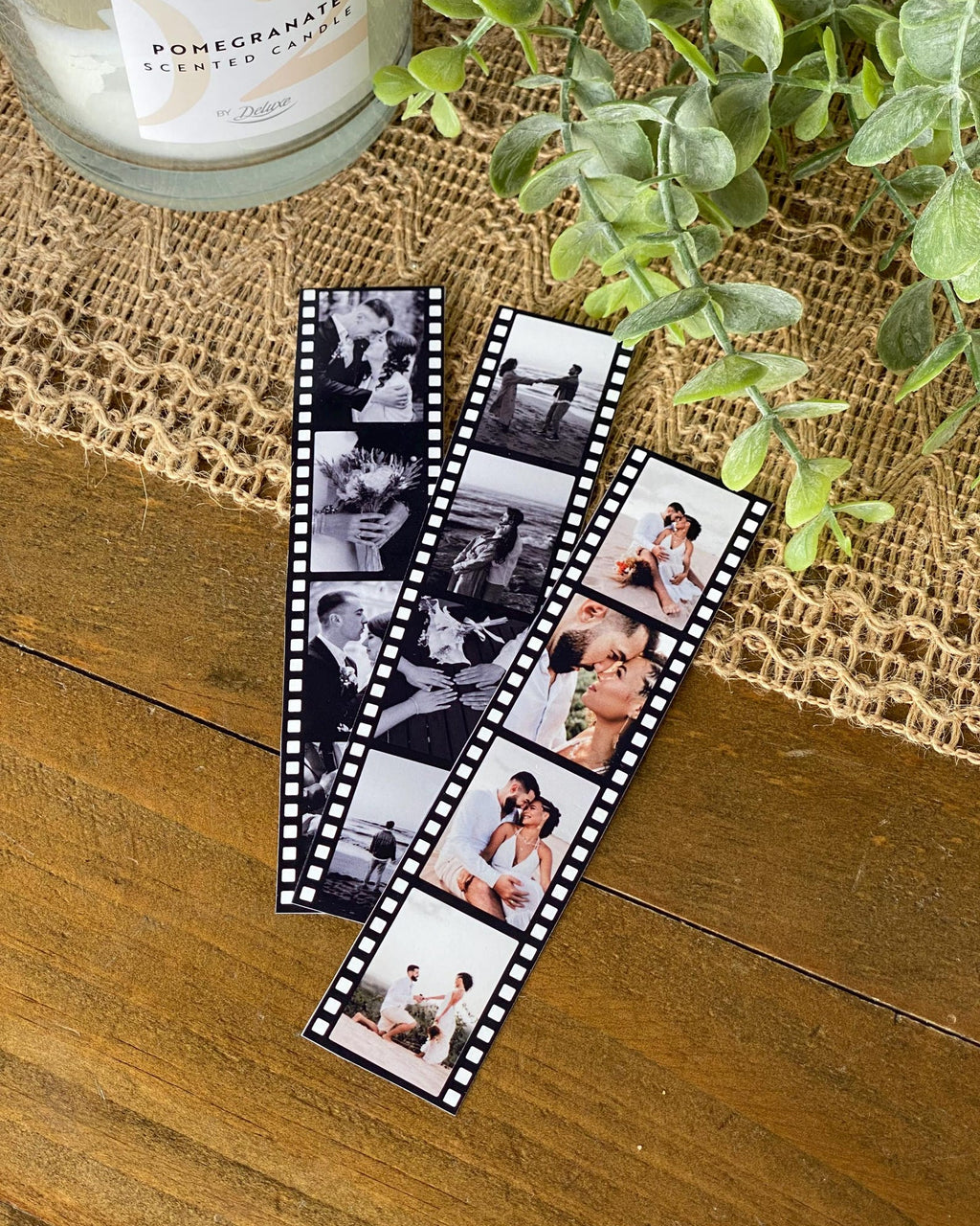 Film strip with black and white photos on a wooden surface with a candle and plant in the background