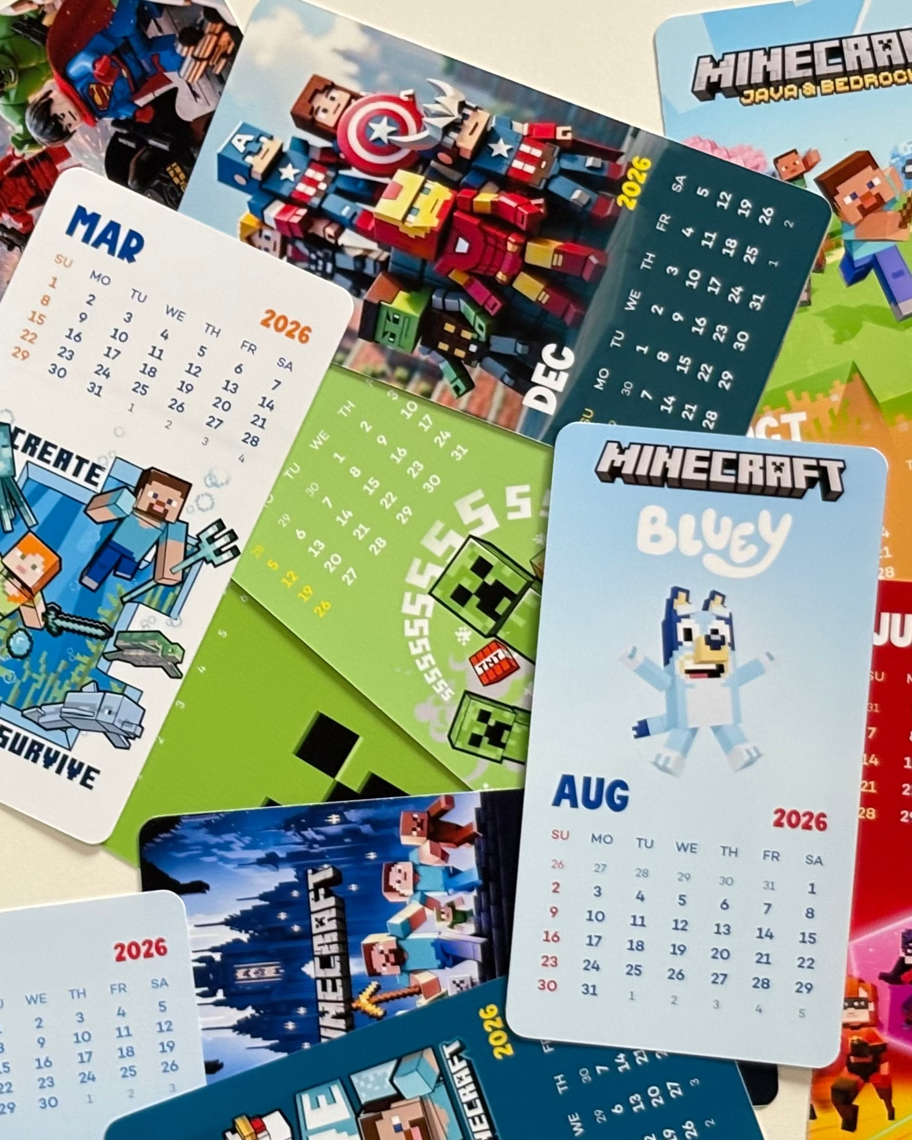 Collection of colorful calendar cards featuring superhero designs on a beige background.