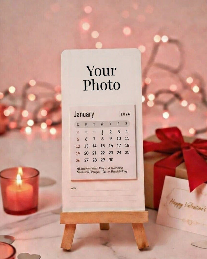 Calendar with 'Your Photo' text on a wooden stand, surrounded by decorative items like candles and a gift box.